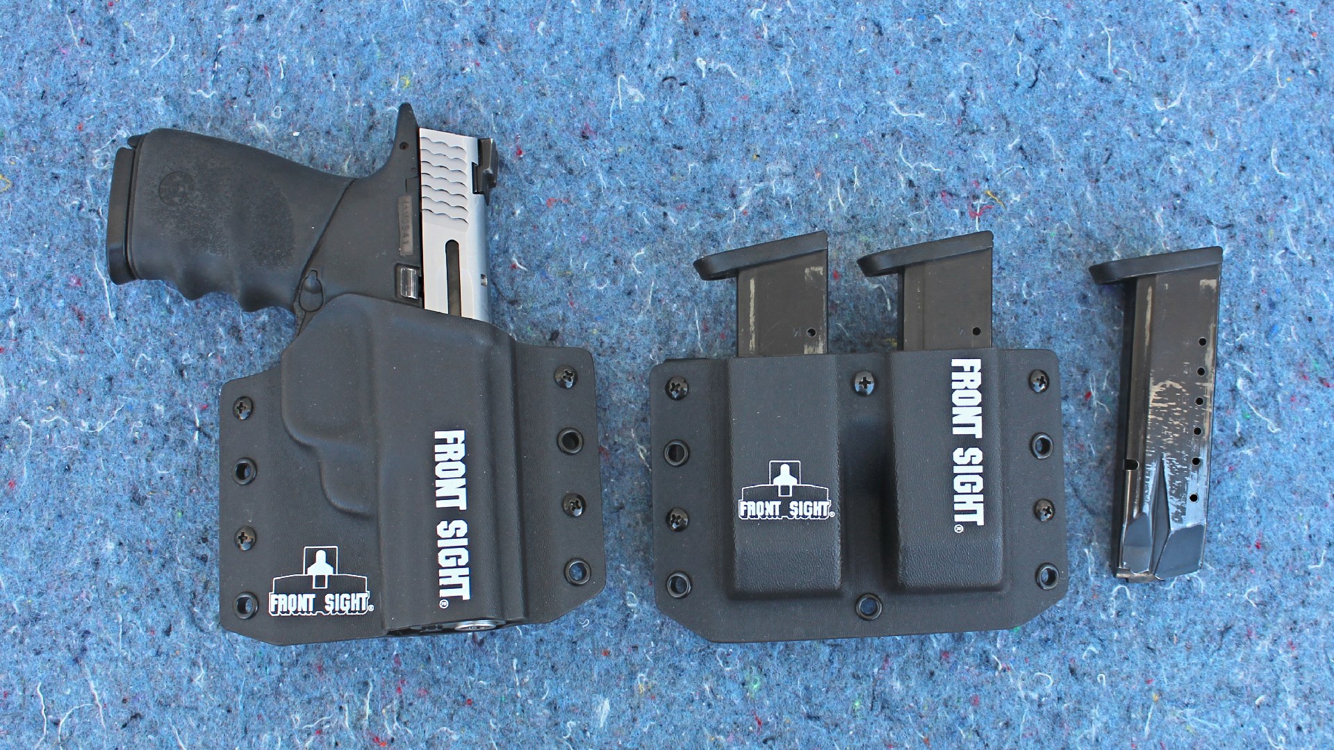 Smith & Wesson M&P 40 two-tone pistol stainless steel slide black frame shown in holster labeled "FRONT SIGHT" alongside magazine holster with verbiage and spare magazines on blue background