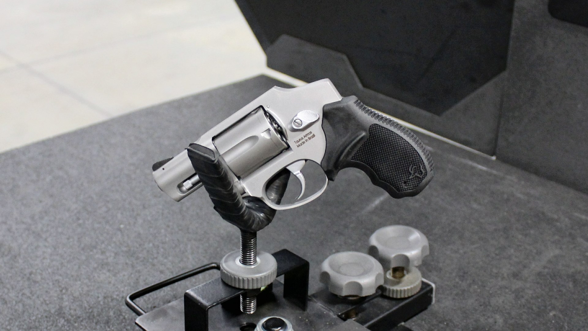 Taurus 605 revolver sitting in a handgun rest on an indoor range bench.