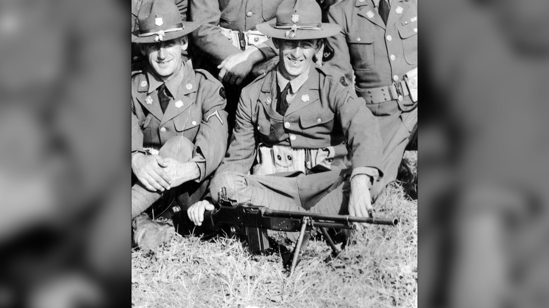 Men from U.S. Army sitting with BAR on bipod on ground men in uniform