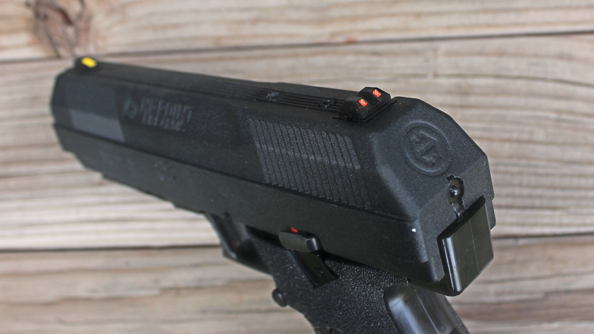 backside view of black pistol hi-point jxp 10 focus on rear sight notch wood background