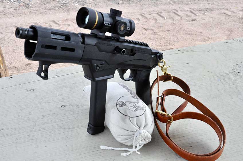Ruger PC Charger pistol with leather sling and optic attached on shooting bench with sandbag