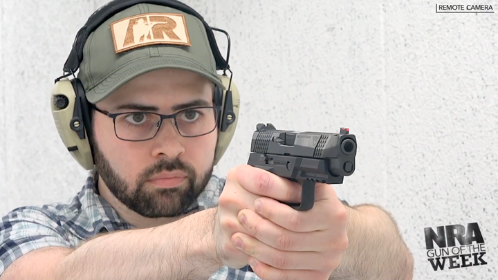 Man wearing ballcap and protective gear holding a gun on a shooting range.