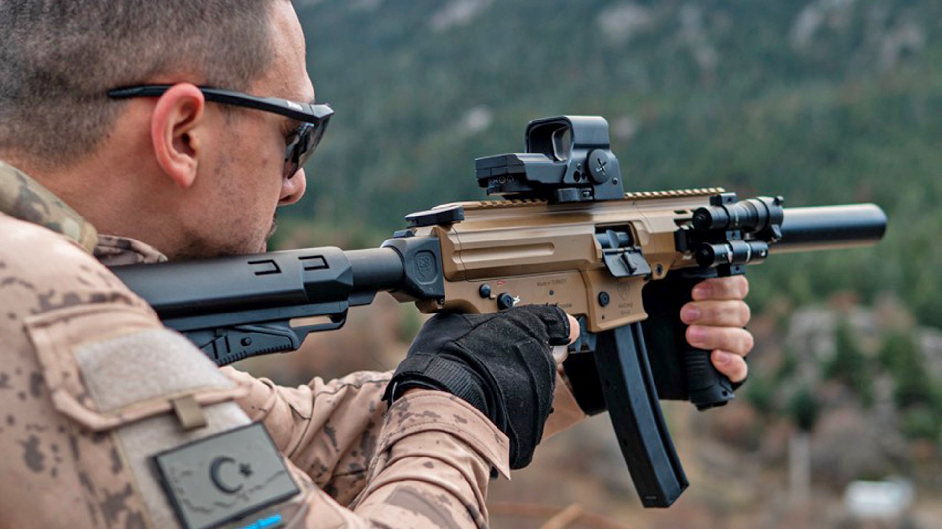 Turkish man wearing camouflage shooting a tan-colored model of the MAC IX.