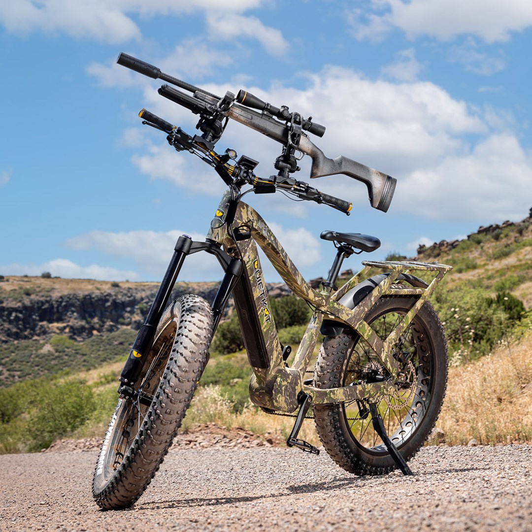 Springfield Model 2020 Redline rifle shown on top of a mountain bike in the middle of a dirt road with a blue sky and white clouds in the background.