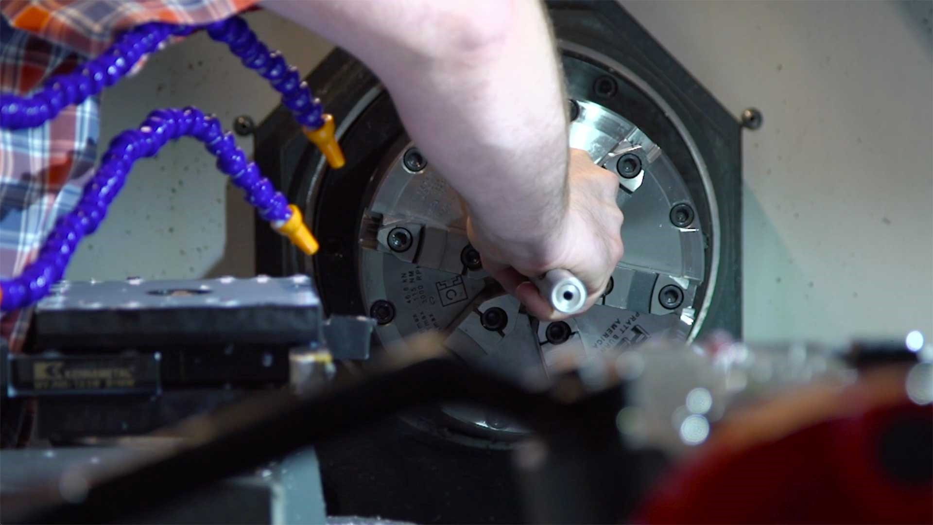 A man placing a rifle barrel inside a machine for barrel threading.