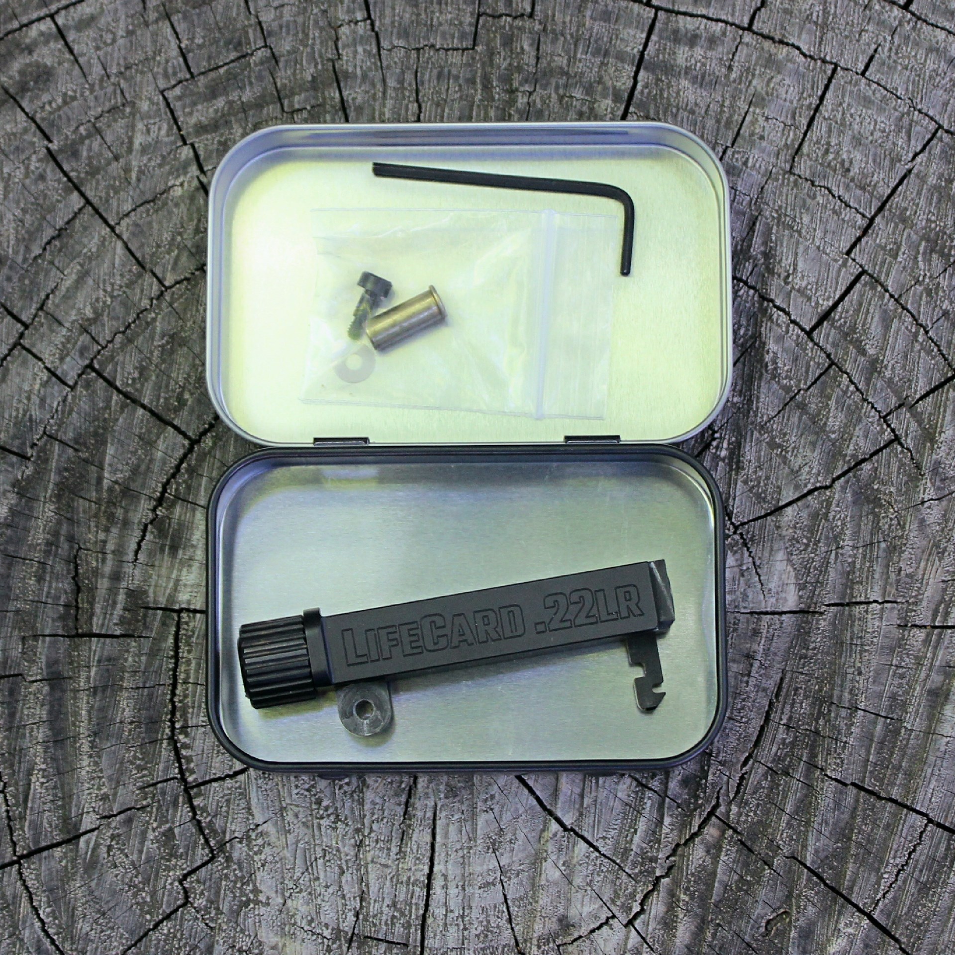 Trailblazer Firearms LifeCard barrel assembly in metal tin container shown with tools and parts on wood log