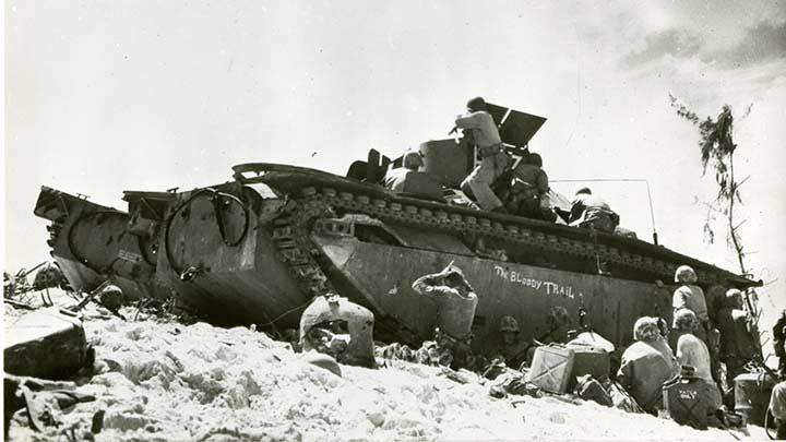 U.S. Marines taking cover behind a knocked out LVT (Landing Vehicle, Tracked) nicknamed “The Bloody Trail” during the first day of the Battle of Peleliu. Note the left-handed Marine firing his M1 rifle. (Marine Corps Photo 21-4).