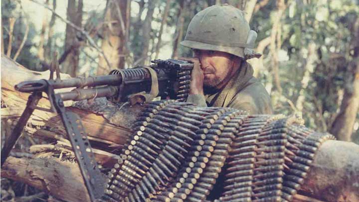 A soldier behind his M60 machine gun with belts of ammunition.