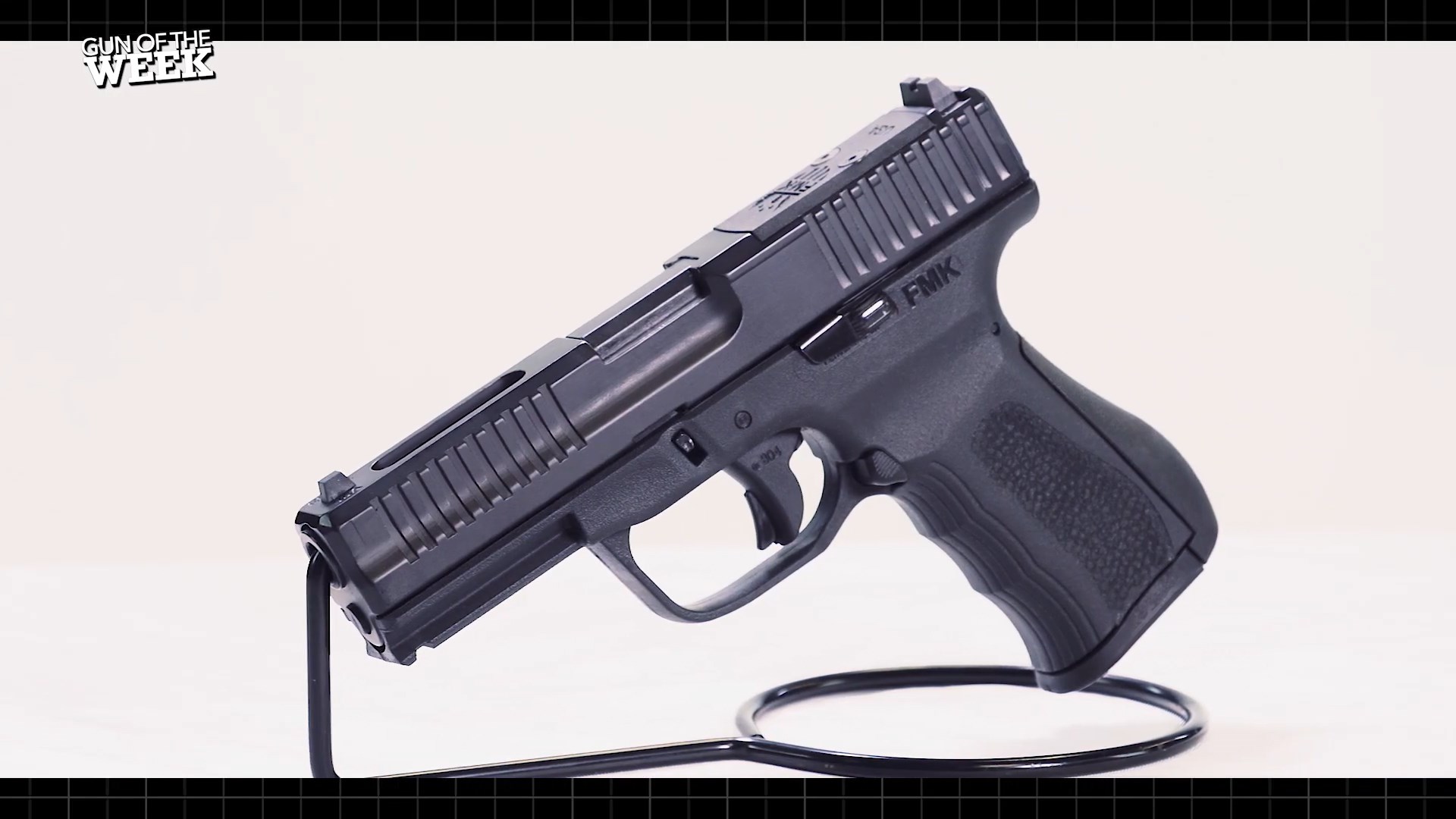 FMK Firearms left-side view black handgun pistol 9 mm gun on stand with white background