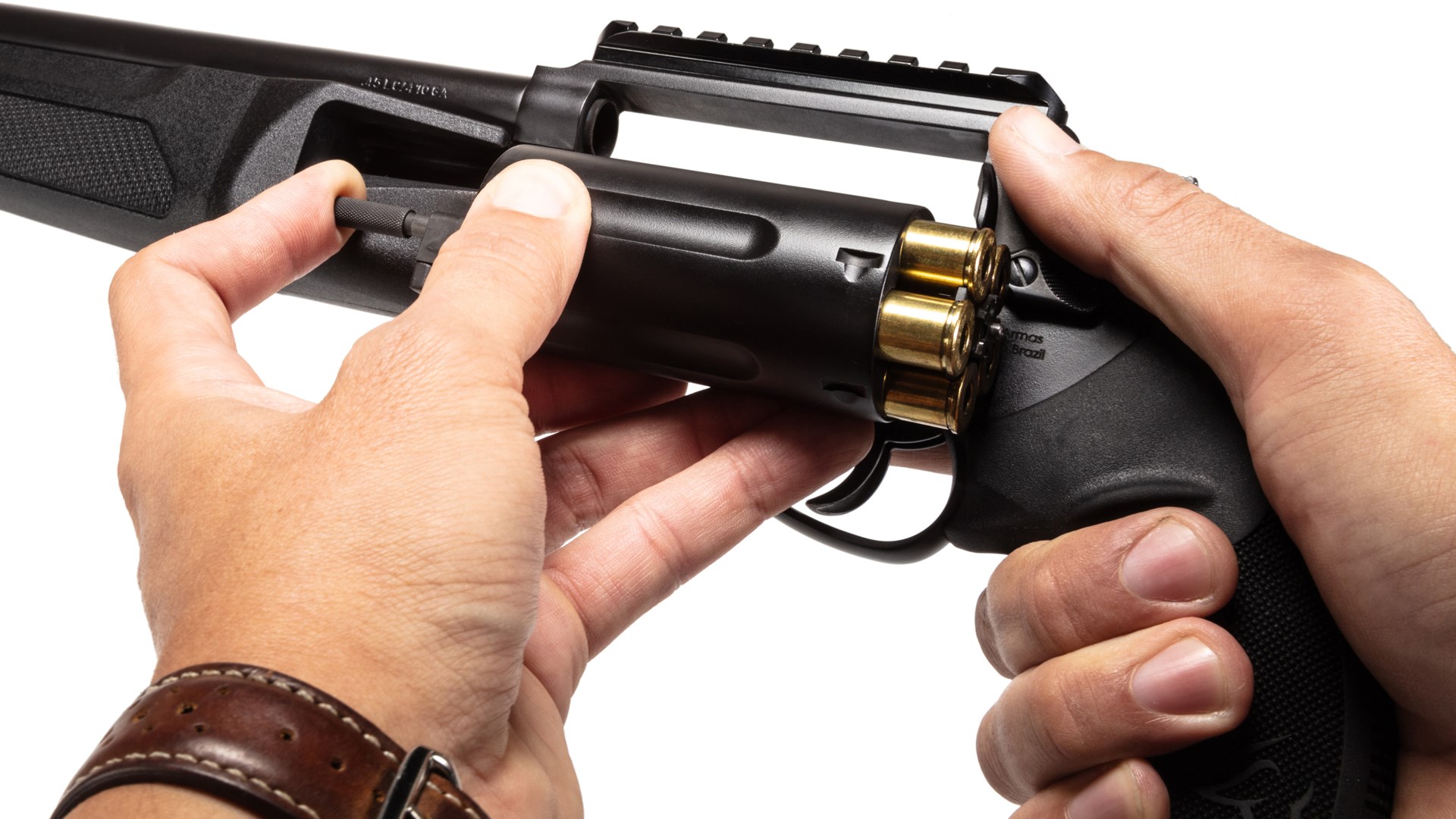 A man pushing the ejector rod on the Taurus Judge Home Defender's cylinder.