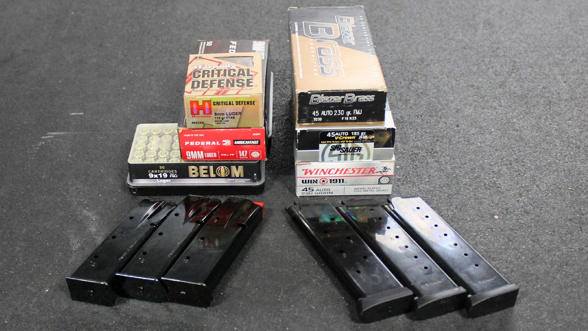 Ammunition boxes .45 ACP and 9 mm Luger shown on black table with four pistol magazines 1911 and high power
