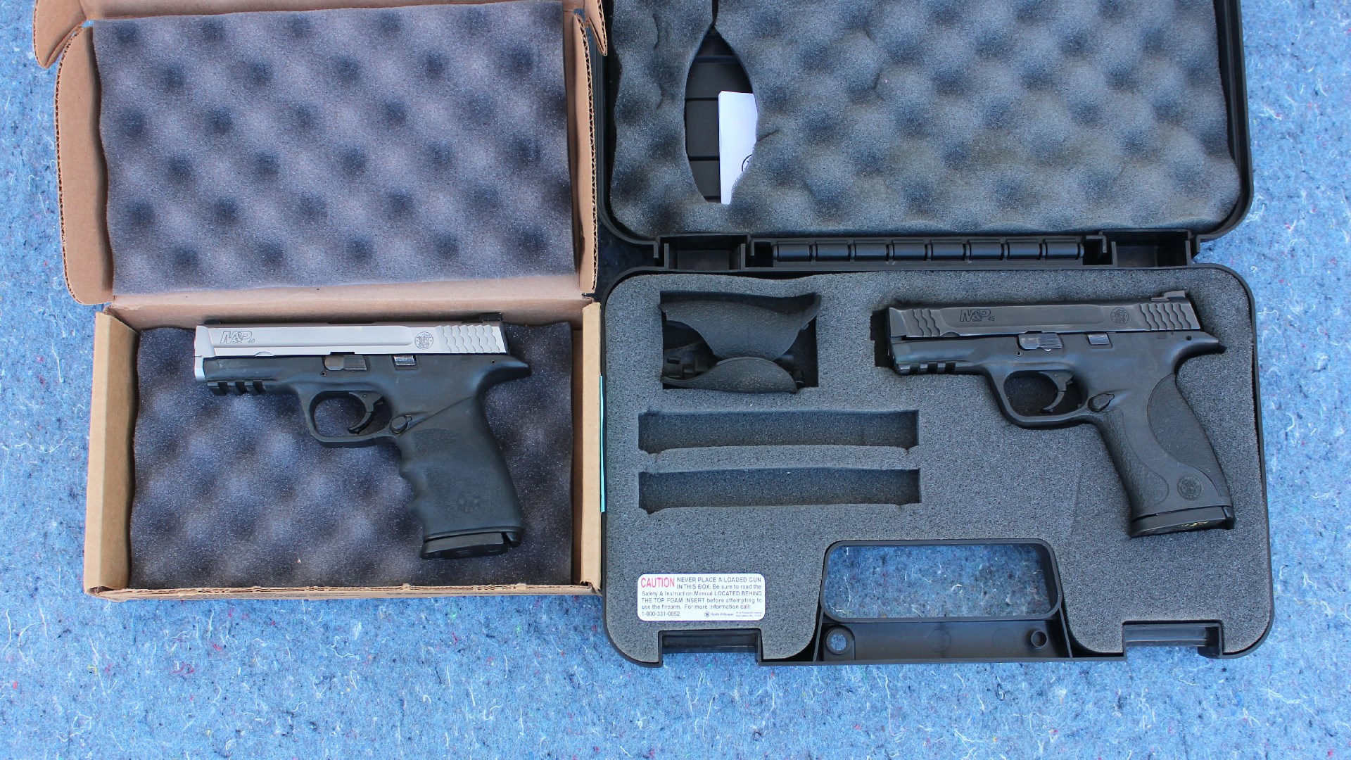 Two pistols guns in respective box and case shown on blue background