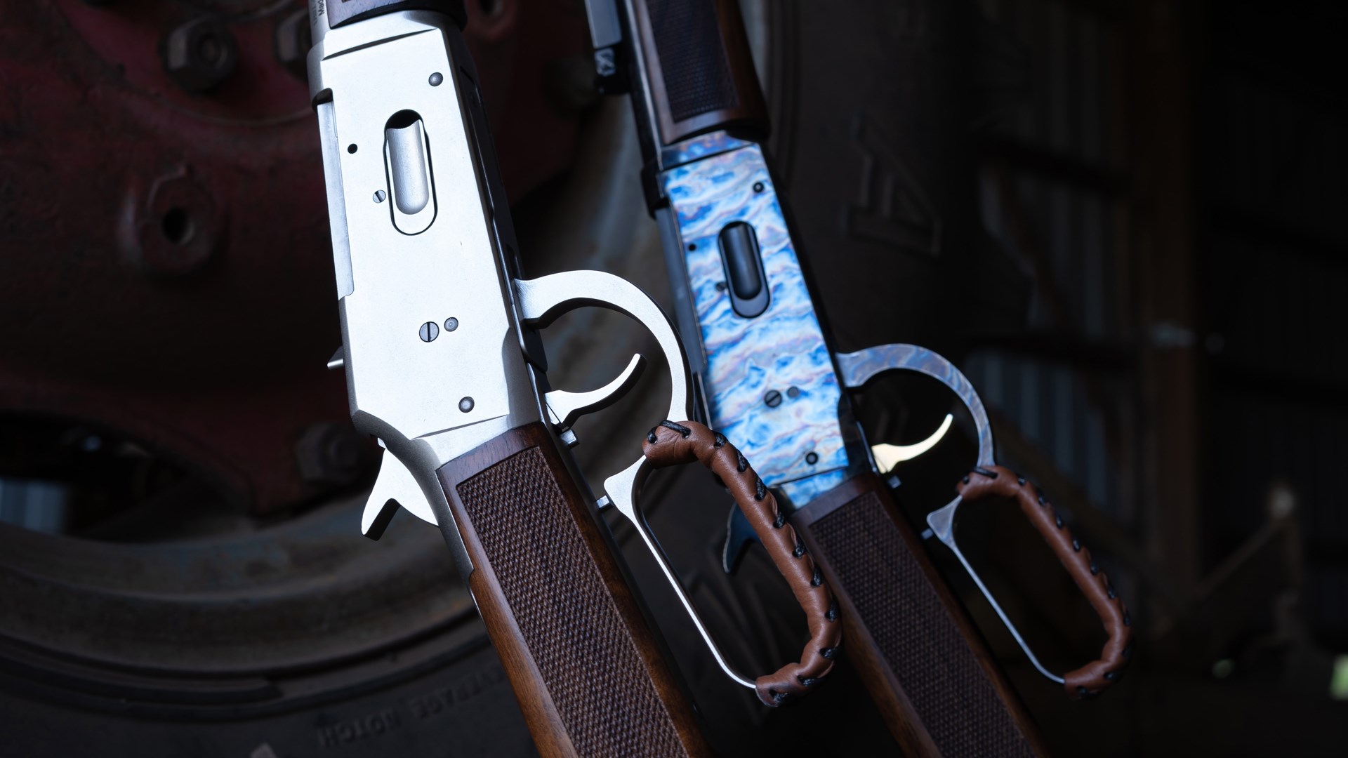 A closeup shot of two TriStar Arms LR94 lever-action shotgun receivers shown on a dark background, one with a nickel finish and another with a case-hardened finish.