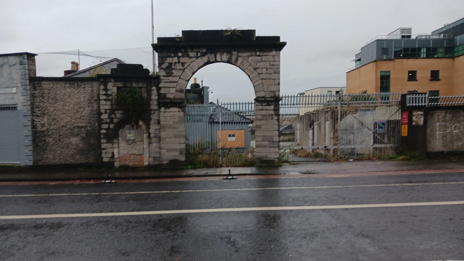gate at clancy barracks armory street view brick buildings wet rain street lines fog clouds