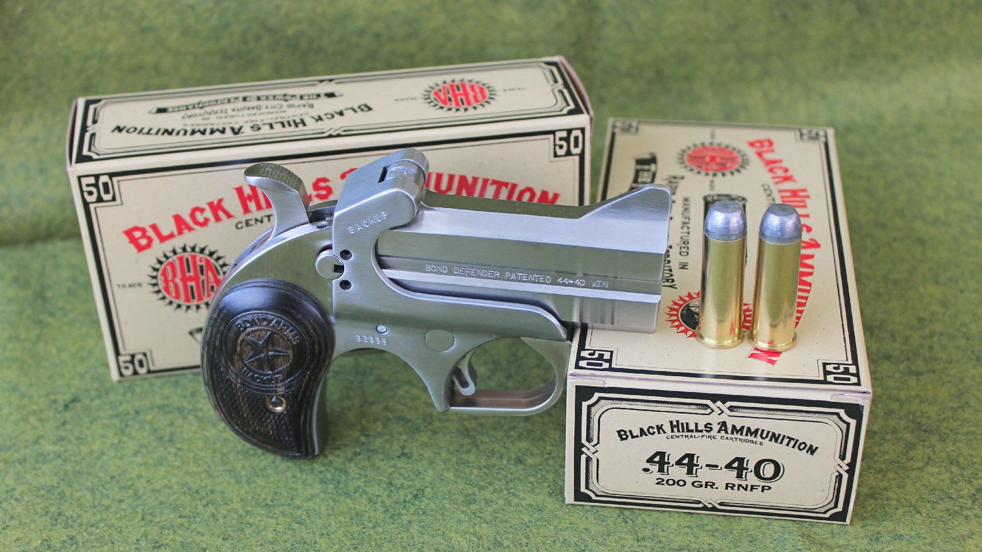 A Bond Arms derringer next to two boxes of Black Hills ammunition.