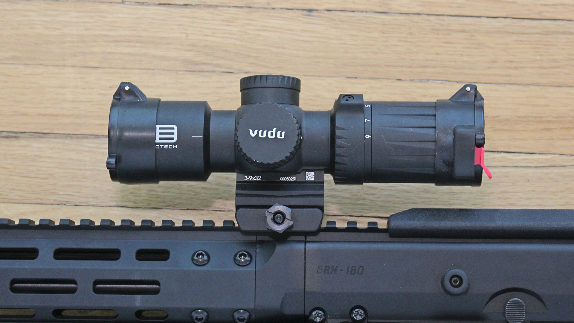 Eotech Vudu riflescope left-side view attached to Picatinny rail atop AR-15 closeup view shown on wood flooring