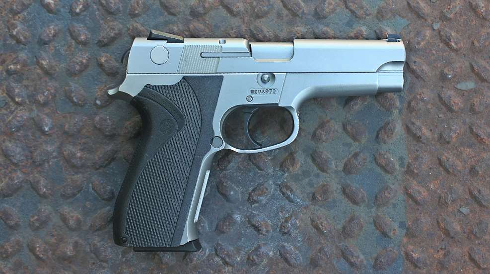 Right-side view of Smith & Wesson Model 5946 Law-Enforcement handgun pistol stainless steel gun on rusty diamondplate steel