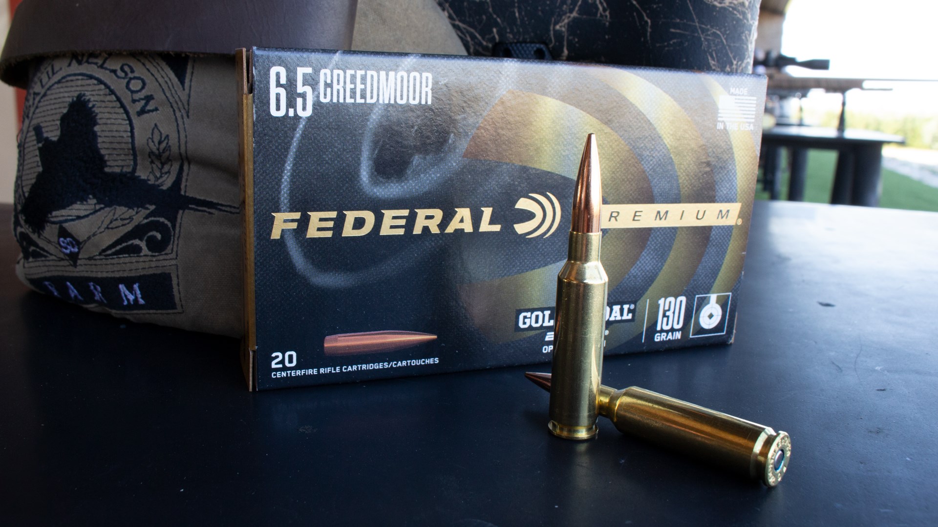 Federal Premium Ammunition box upright cartridge bullet 6.5 mm Creedmoor Berger bullet on bench outdoor rifle background bag