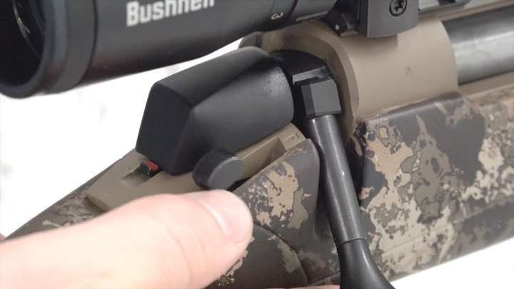 Up-close view of rifle&#x27;s safety with a shooter&#x27;s thumb behind.