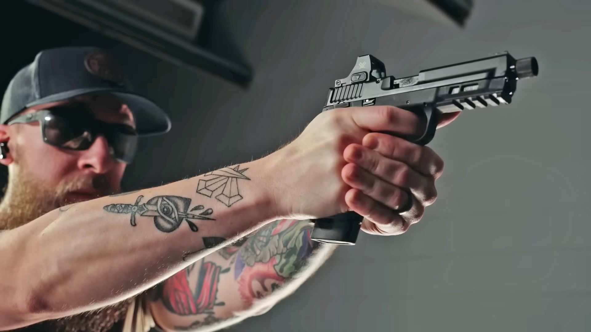Man with arm tattoos aiming the Smith & Wesson M&P 22X.