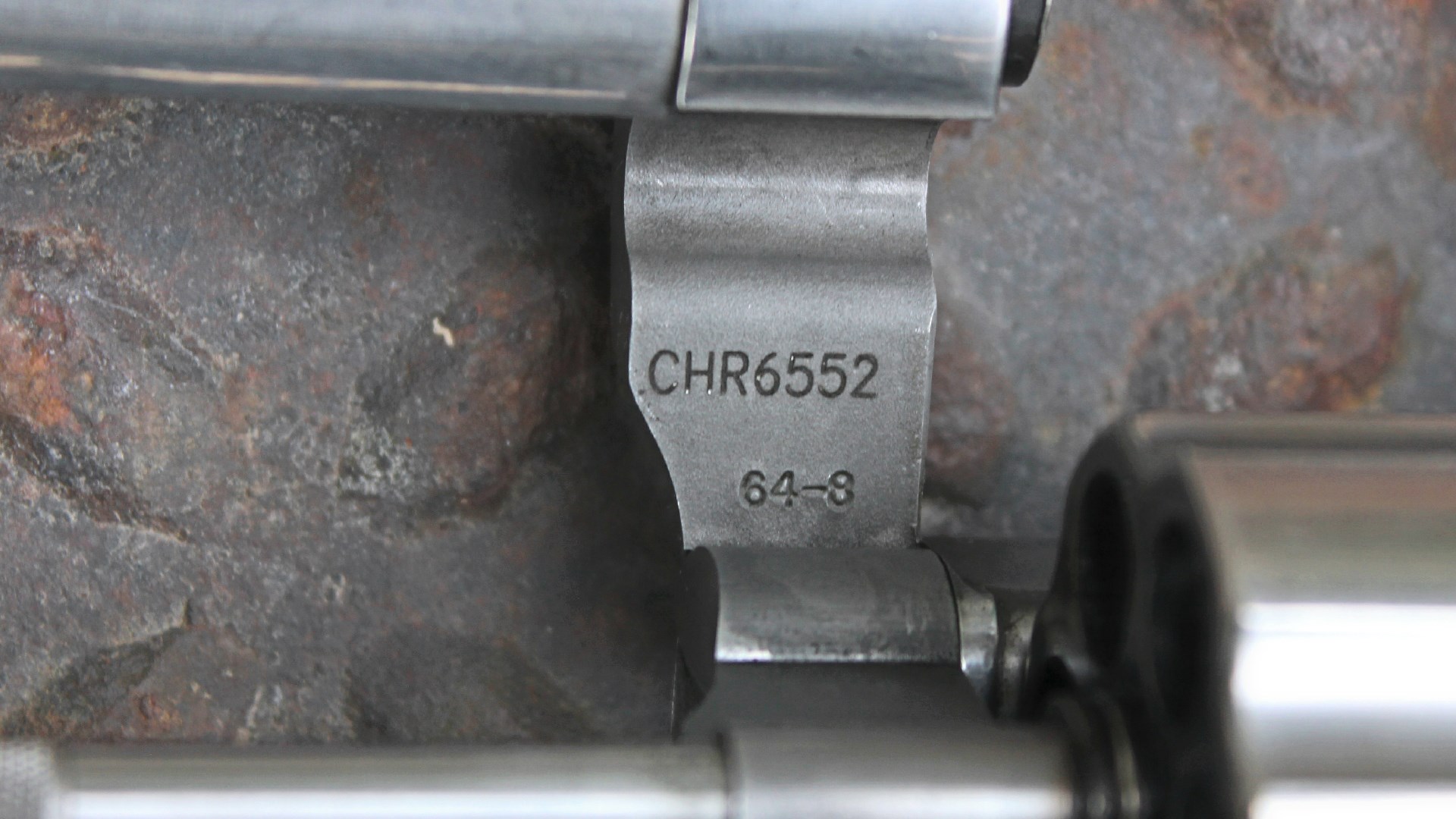 Smith & WEsson 65-8 stamp serial number on stainless steel crane mechanism of revolver left-side view shown on rusted treadplate