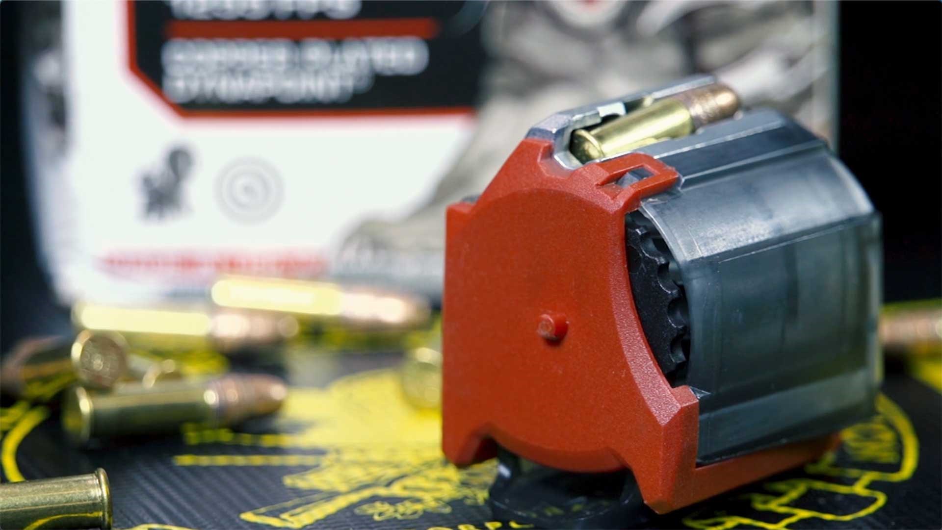 Winchester's Wildcat 22 SR red rotary magazine shown on a black table with cartridge around it.