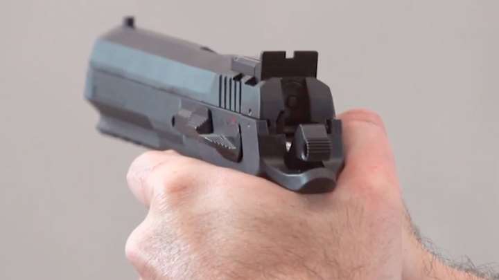 Rear view of EAA pistol in hands focusing on rear sight and hammer.