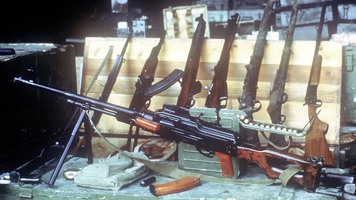 A PKM machine gun posed alongside a broad range of long arms captured on Grenada, including an SMLE Mk III, a Martini-Henry rifle, a commercial shotgun and a Czech vz. 52/57.
