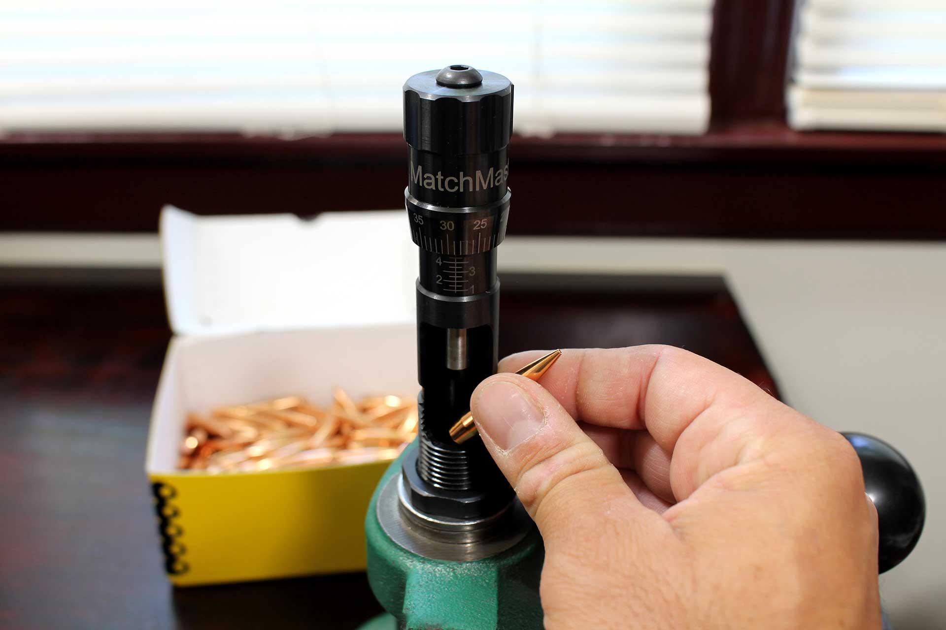 Inserting a bullet into the RCBS Matchmaster bushing die while mounted on a reloading bench press.