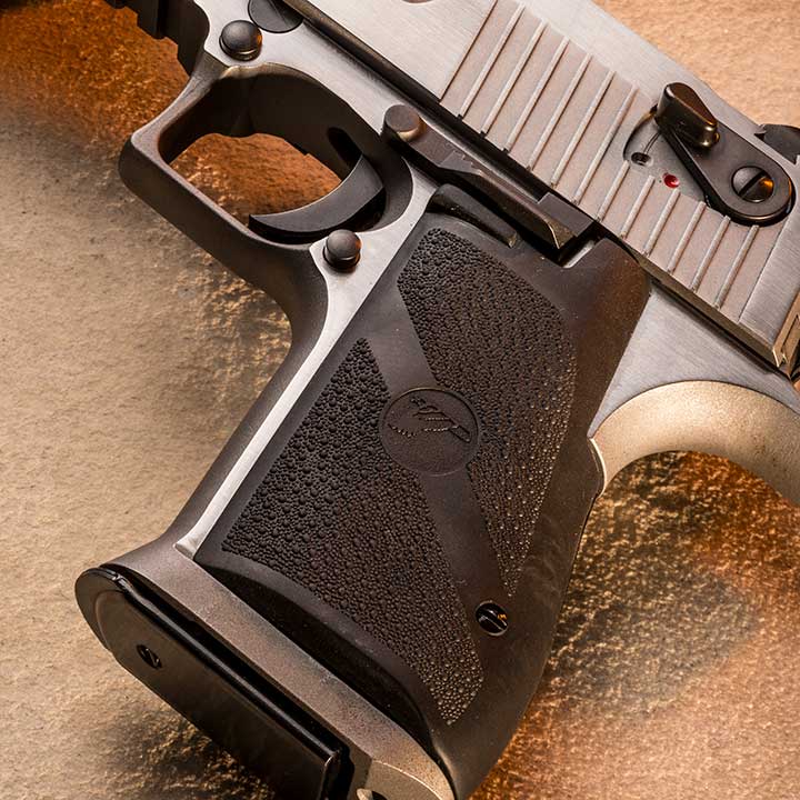 Grip of the Magnum Research Desert Eagle shown on a sand background, along with an inserted magazine.
