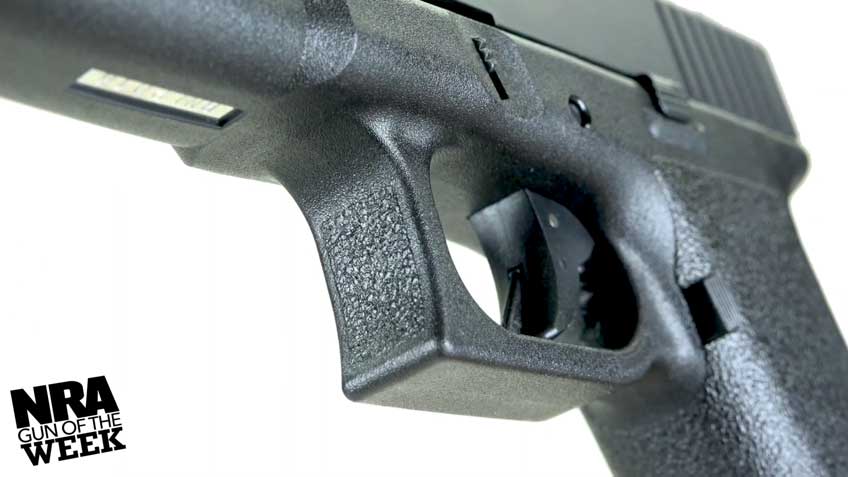 black pistol trigger closeup plastic white background text on image noting NRA Gun of the Week