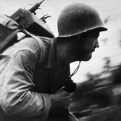 A 1st Marine Division radioman with a Motorola SCR-300 &quot;Walkie-Talkie&quot; backpack radio rushes forward during the battle of Peleliu. (National Archives File #80-G-48359/WAR &amp; CONFLICT #1181).