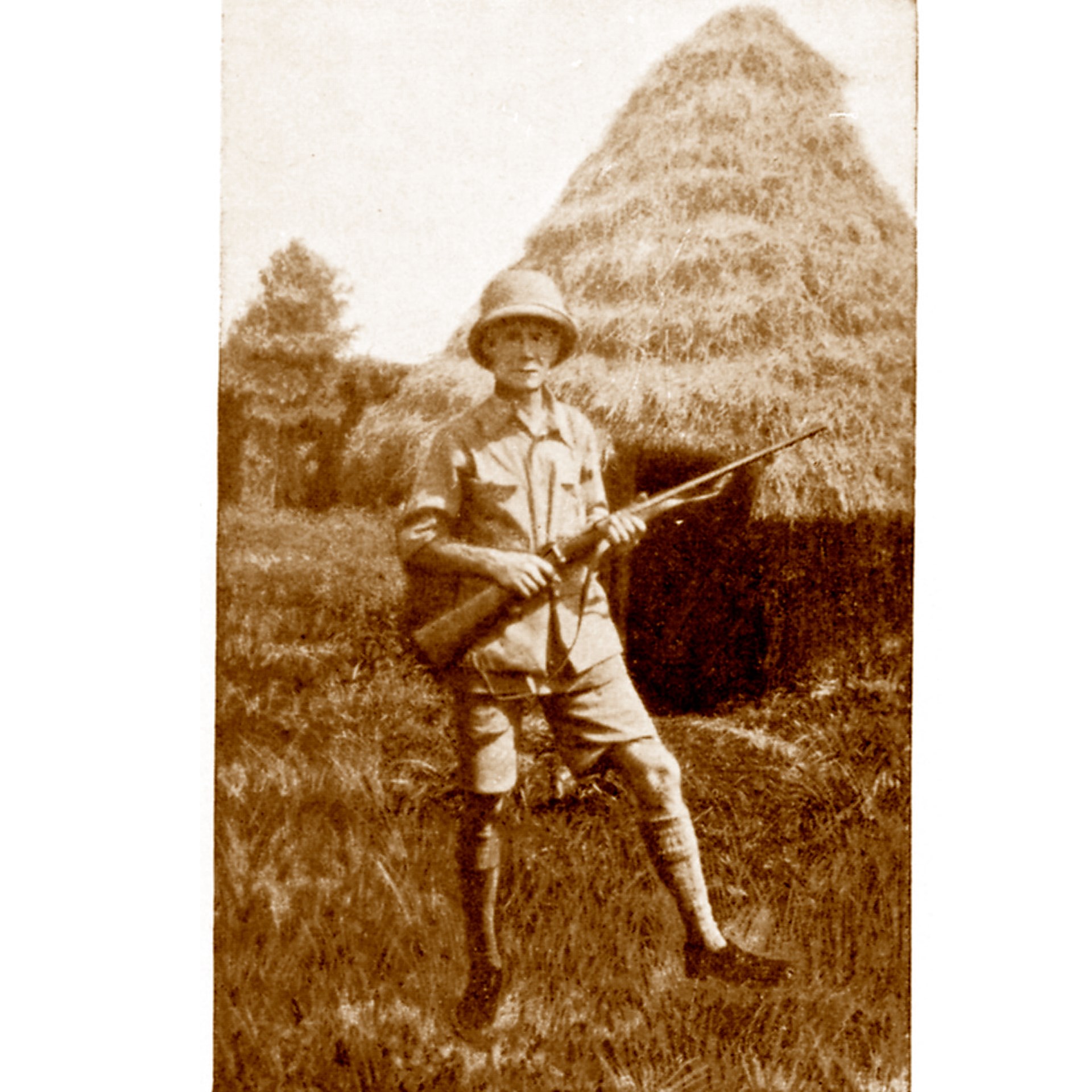 Man outdoors in front of grass hut safari hunter africa mauser rifle