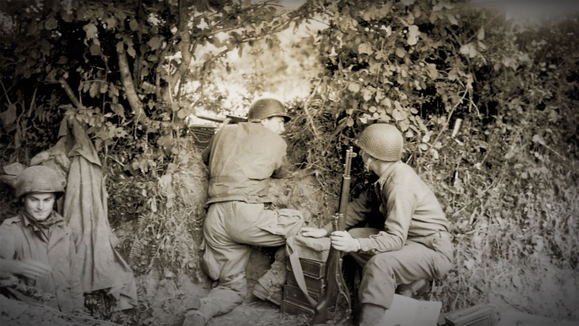 U.S. infantrymen, one with a M1 Garand and the other manning a M1919A4 machine gun, seen during fighting in the dense hedgerows of the Bocage region.