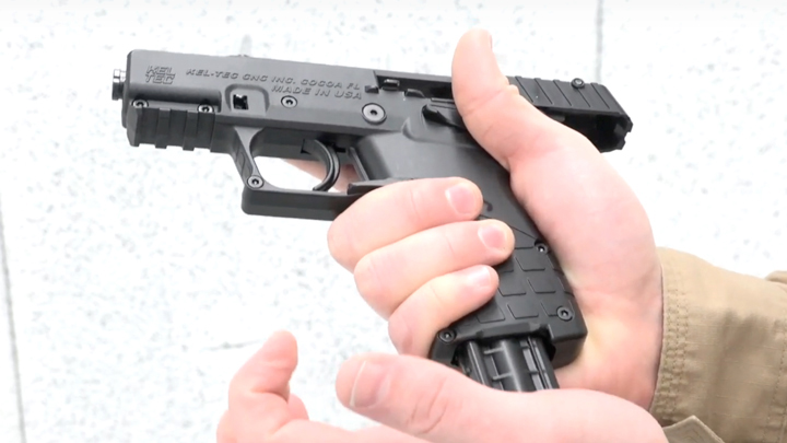 Left-side view of Kel-Tec P17 pistol in right hand of shooter with left hand inserting magazine.