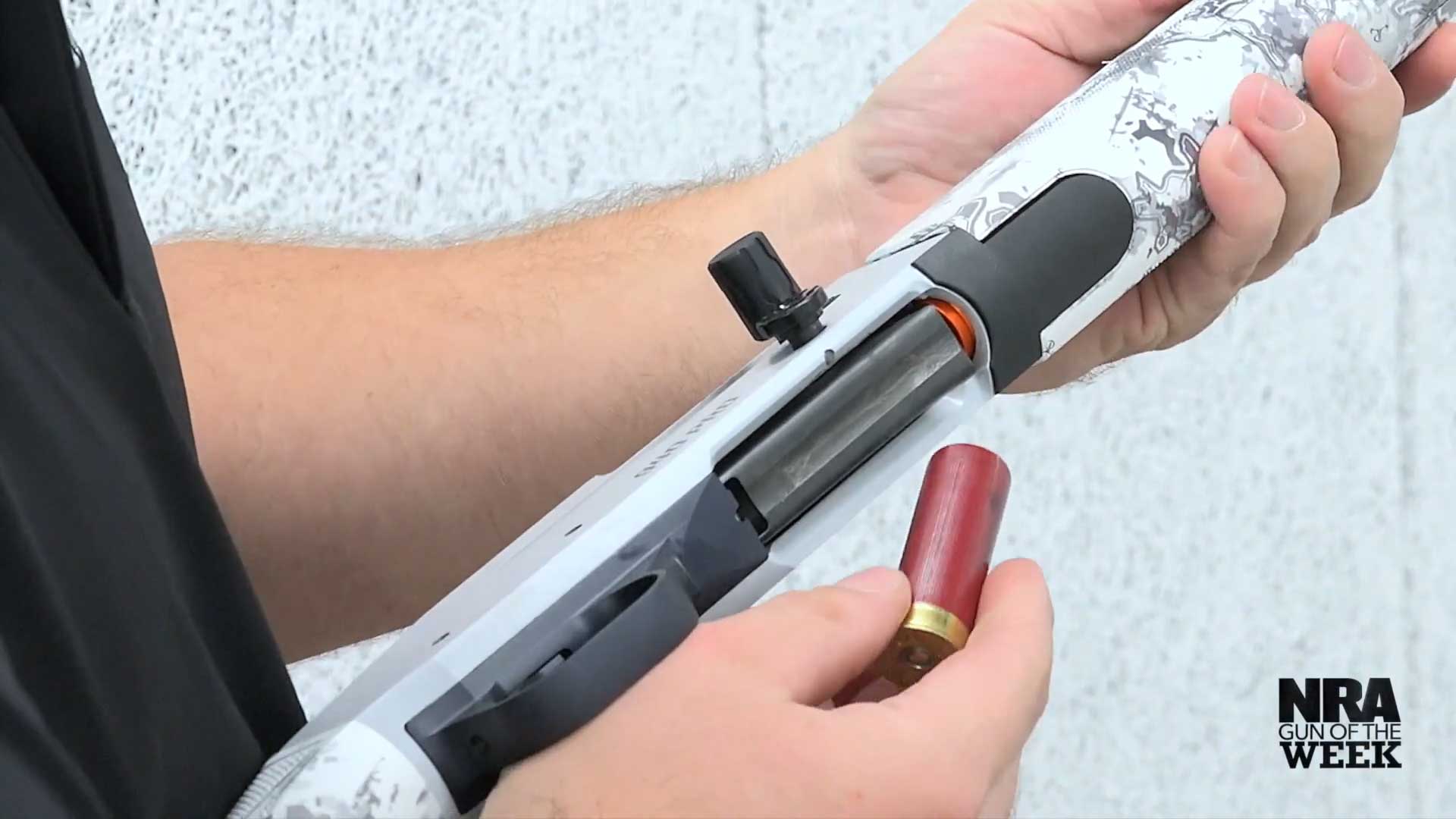 arms holding white gray shotgun loading ammunition