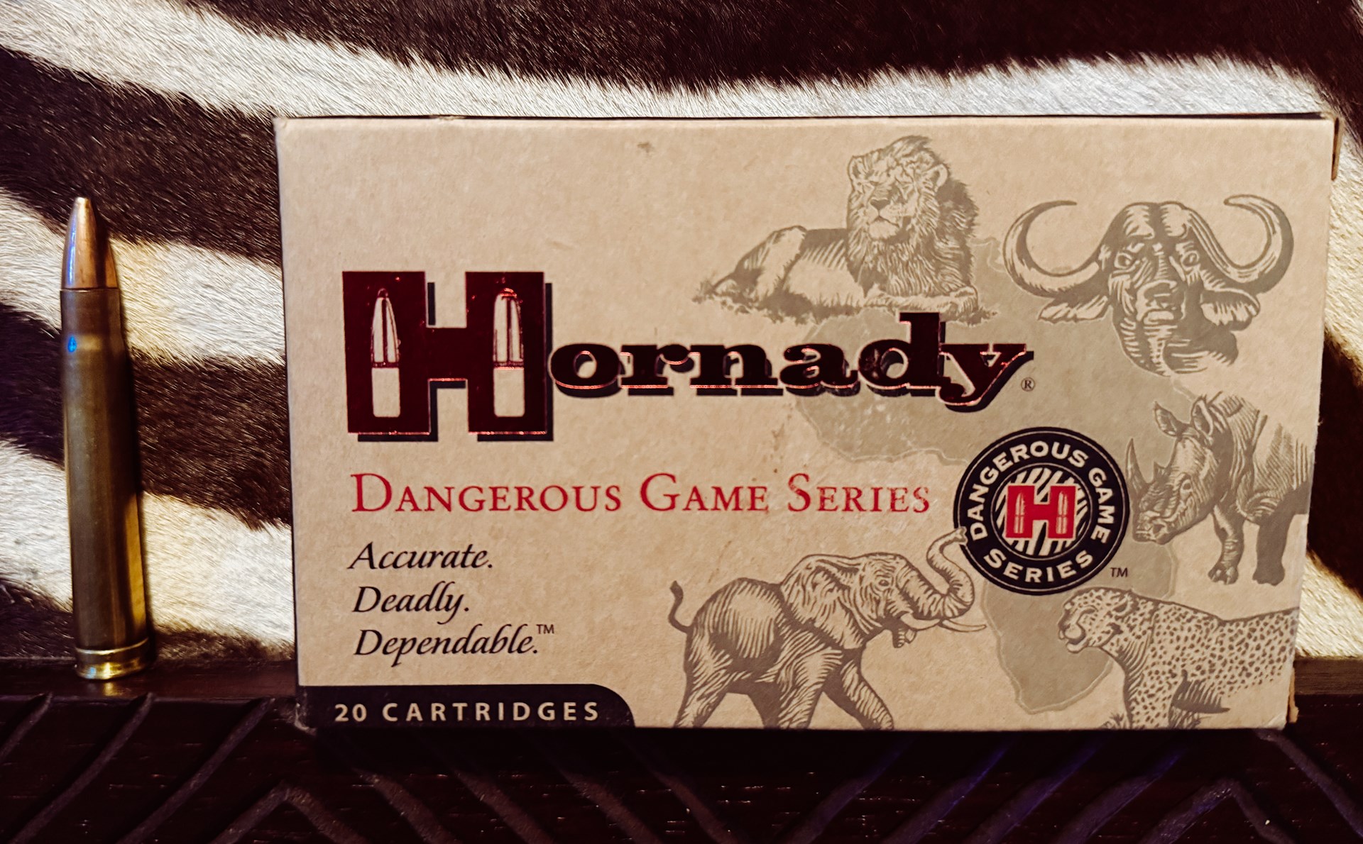 Hornady Dangerous Game Series ammunition box shown next to .375 H&H Mag. cartridge in front of zebra pelt